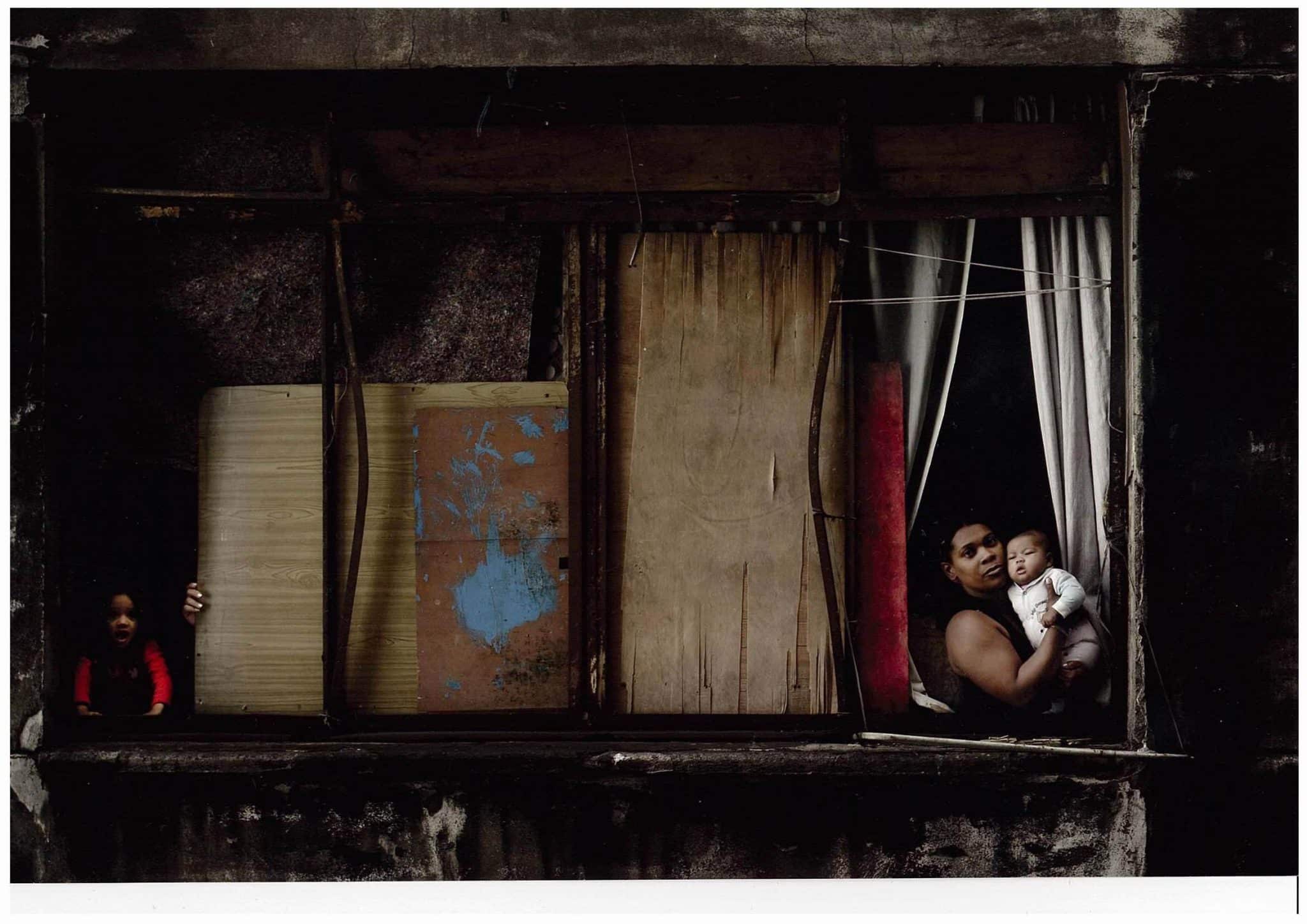 In a Window of Prestes Maia 911 Building, Mara holds her daughter © Julio Bittencourt