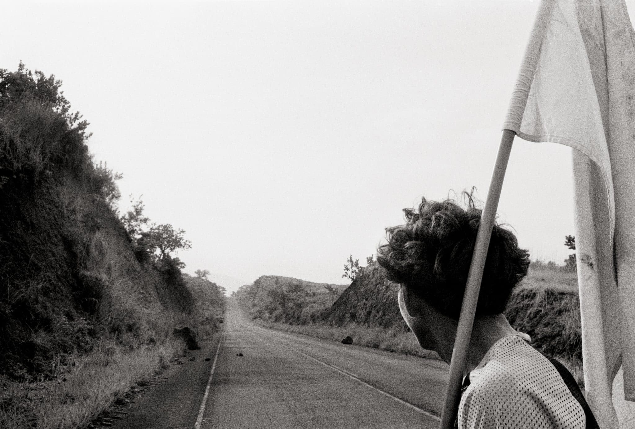 A Salvadoran journalist displays a white flag to show FPL guerrillas that
he travels in peace on the Pan American Highway. Department of San Vicente,
June 1983 © Robert Nickelsberg