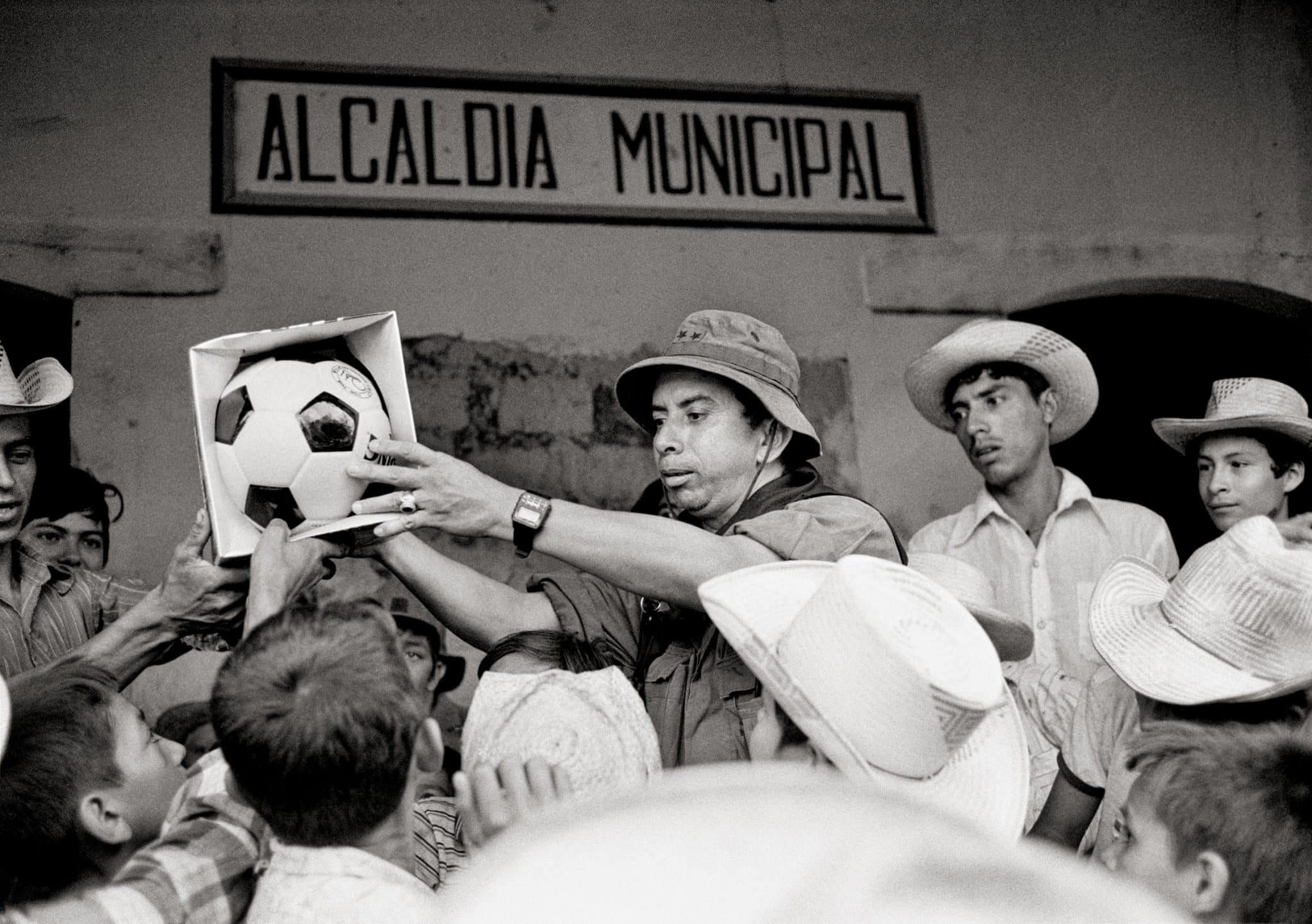 Oberstleutnant Domingo Monterrosa, Kommandeur des Atlacatl-Bataillons, übergibt im Rahmen einer zivilen Befriedungsaktion in der Nähe des Guerillagebiets einen neuen Fußball an einheimische Kinder. Joateca, Departement Morazán, Oktober 1984 © Robert Nickelsberg